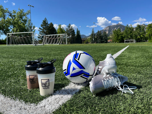 VUUR shakes beside soccer cleats and a soccer ball on a field, highlighting sports nutrition for active teenagers and pre-practice fuel for teen athletes.
